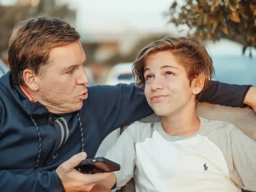 Parent et enfant assis ensemble dans un jardin d'été, partageant un moment de conversation tranquille