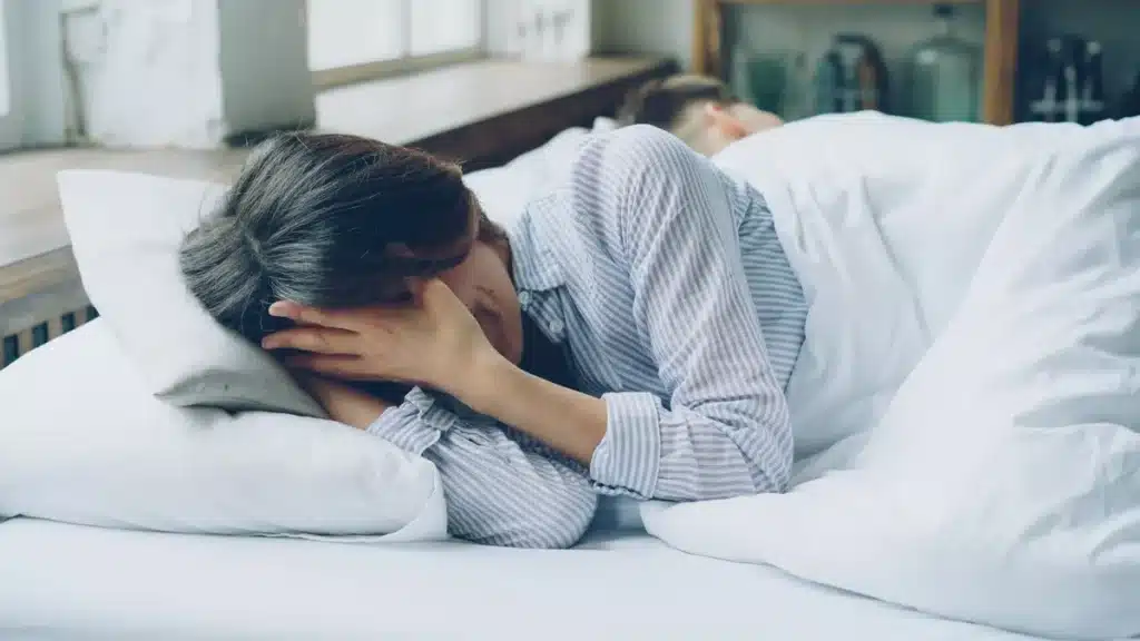 Chambre fraîche avec stores fermés, verre d'eau et literie légère pour se protéger de la chaleur
