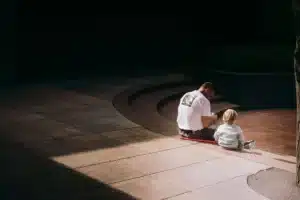 Parent s'éloignant d'une situation tendue dans une maison, enfant en arrière-plan dans un endroit sûr.