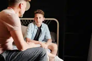 Parent et enfant en discussion sérieuse à table, illustrant un moment de négociation et de limites