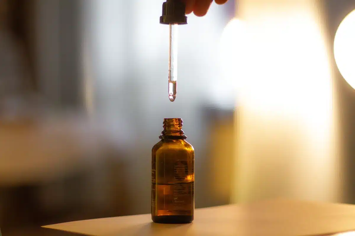 Flacon avec pipette versant des gouttes dans un verre d'eau