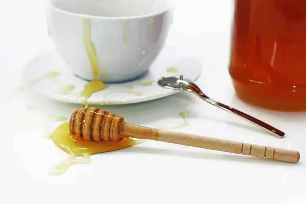 Miel cristallisé dans un bocal en verre avec des cristaux visibles et une cuillère en bois