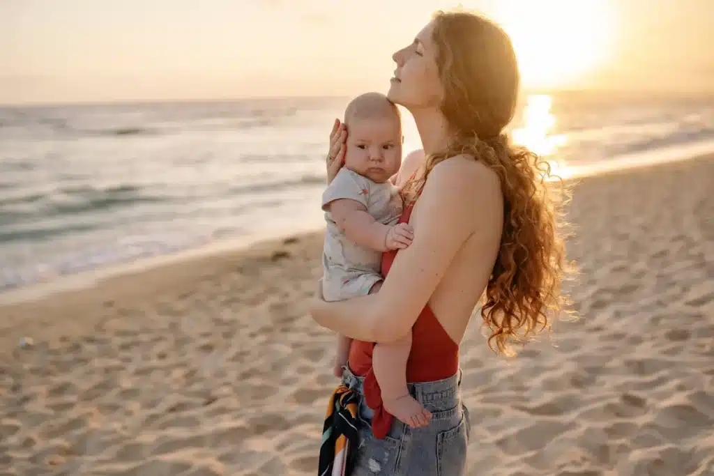 Un enfant et un parent marchent pieds nus sur la plage au coucher du soleil