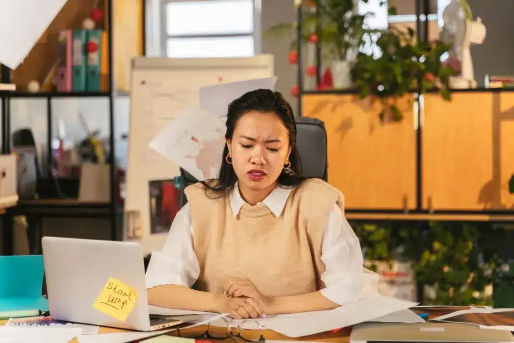 Personne assise à un bureau, épaules tendues, main sur l'abdomen, montrant les effets physiques du stress