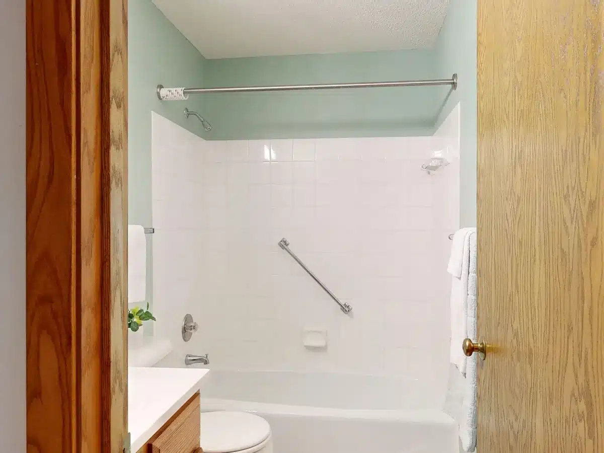 Salle de bain aménagée avec barres d'appui et éclairage sécurisé pour personne âgée.