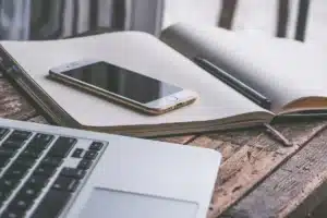 Espace de travail anonyme avec ordinateur, checklist d'accessibilité et mains prenant des notes