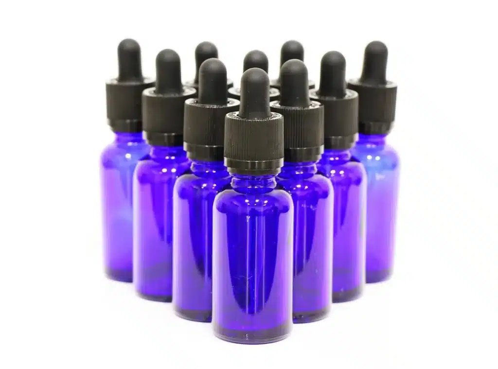 Rayon de boutique avec petites bouteilles d'huile et pipettes, main anonyme saisissant un flacon