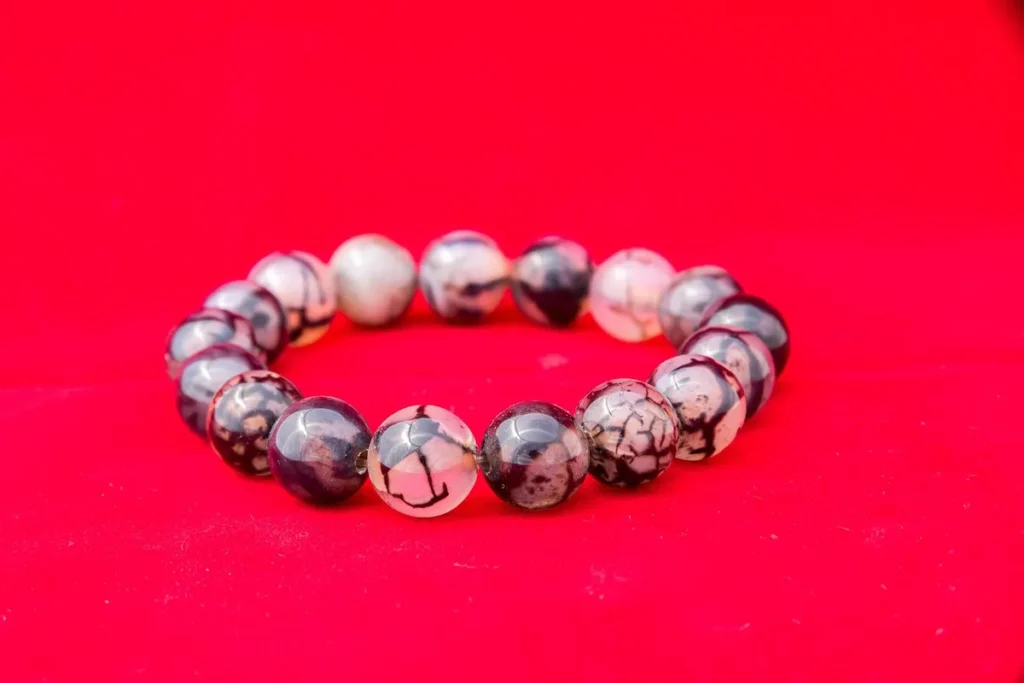 Bracelet en perles de bois et de pierre naturelle, posé sur une surface neutre avec détails de texture visibles.