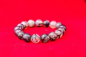 Bracelet en perles de bois et de pierre naturelle, posé sur une surface neutre avec détails de texture visibles.