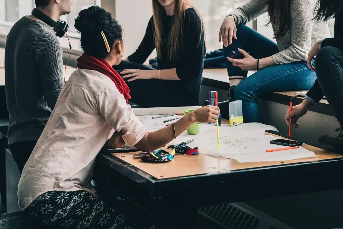 Groupe de personnes en réunion participative discutant et échangeant des idées autour d'une table.