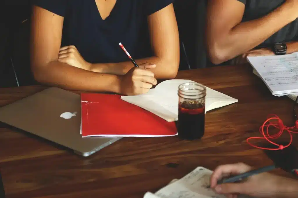 Personnes réunies autour d'une table de conférence avec documents, écoutant et prenant des notes lors d'une réunion inst