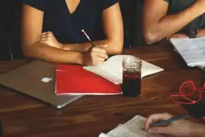 Personnes réunies autour d'une table de conférence avec documents, écoutant et prenant des notes lors d'une réunion inst
