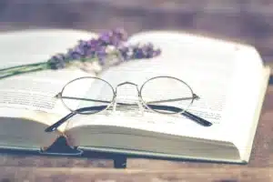 Paire de lunettes de lecture et appareil auditif posés côte à côte sur une surface lumineuse