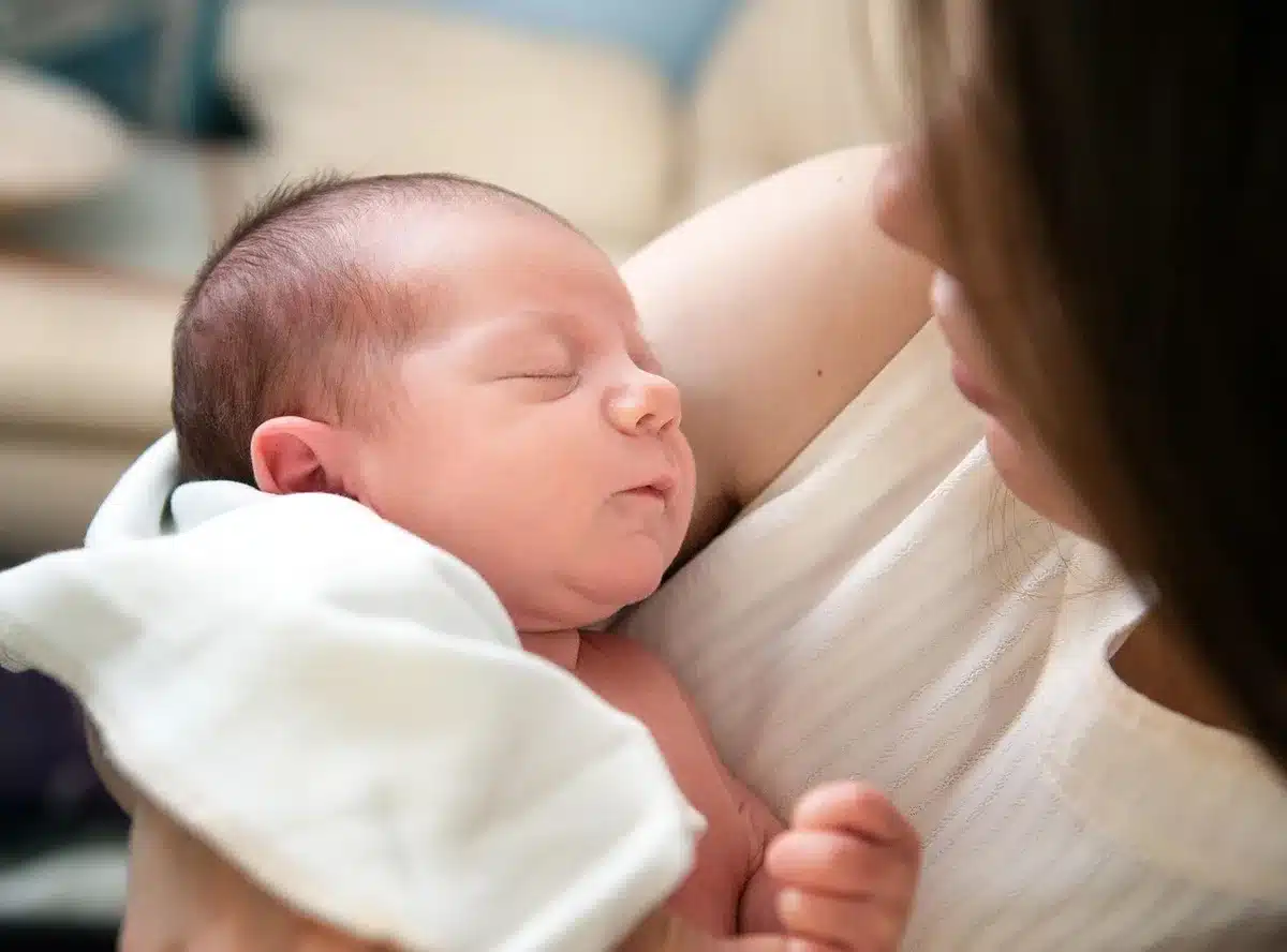 Parent debout coupant légèrement une mèche de cheveux d'un bébé assis en chaise haute