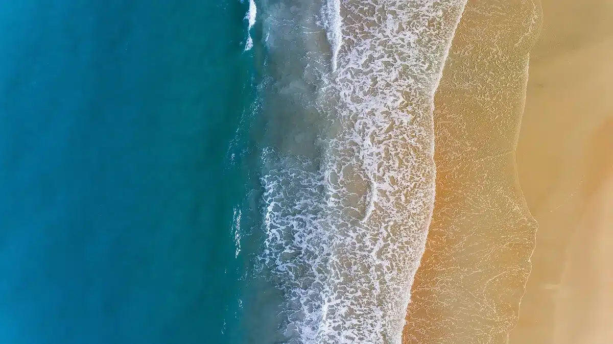 Mousse blanche accumulée sur le sable d'une plage