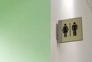 Serviette hygiénique, carnet et verre d'eau posés sur un lavabo, main anonyme atteignant la serviette