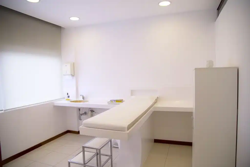 Table de consultation réglable dans un cabinet baigné de lumière naturelle, accessoires ergonomiques en arrière‑plan