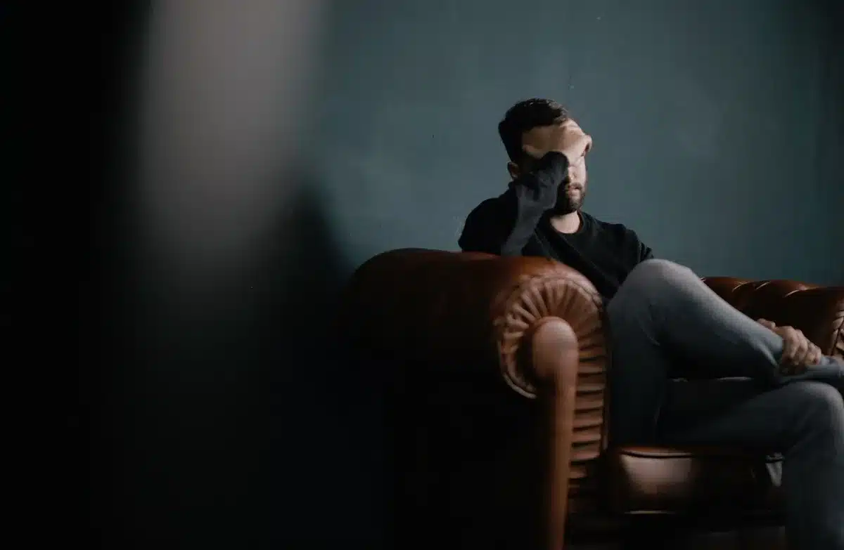 Homme assis fatigué tenant sa tête, évoquant fatigue et baisse de désir