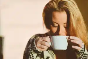 Mains tenant une tasse et un carnet sur un banc ensoleillé dans un parc