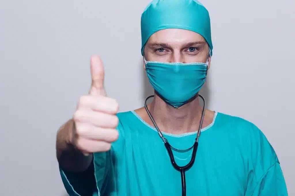 Mains posées sur un bureau de consultation, questionnaire de santé et stéthoscope en arrière-plan
