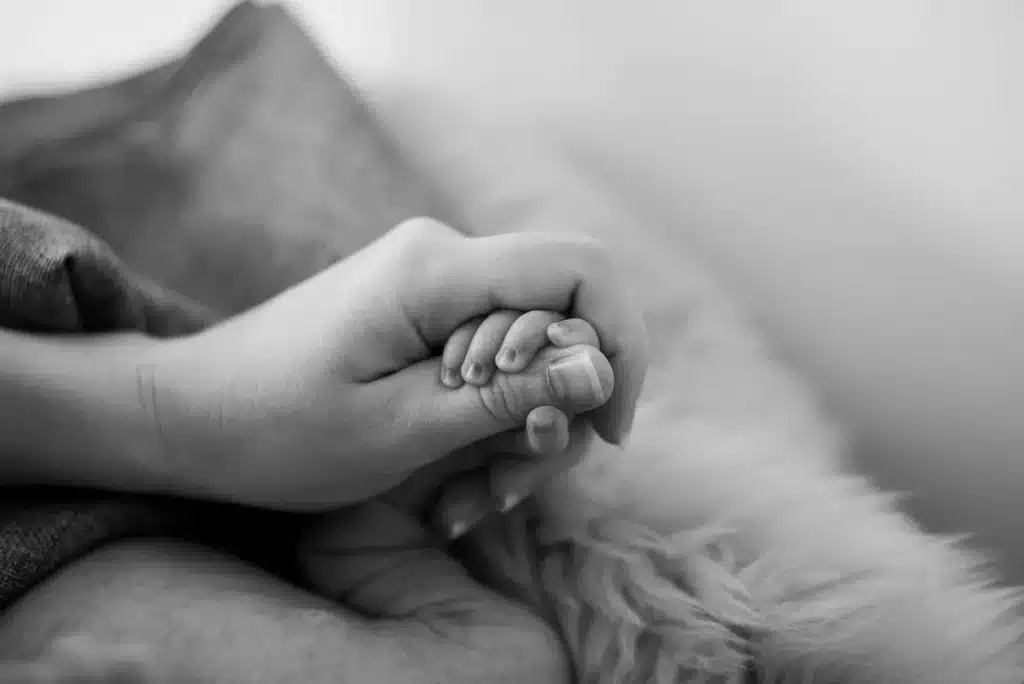 Un adulte tenant les mains d'un enfant près d'une fenêtre en plein jour pour le rassurer