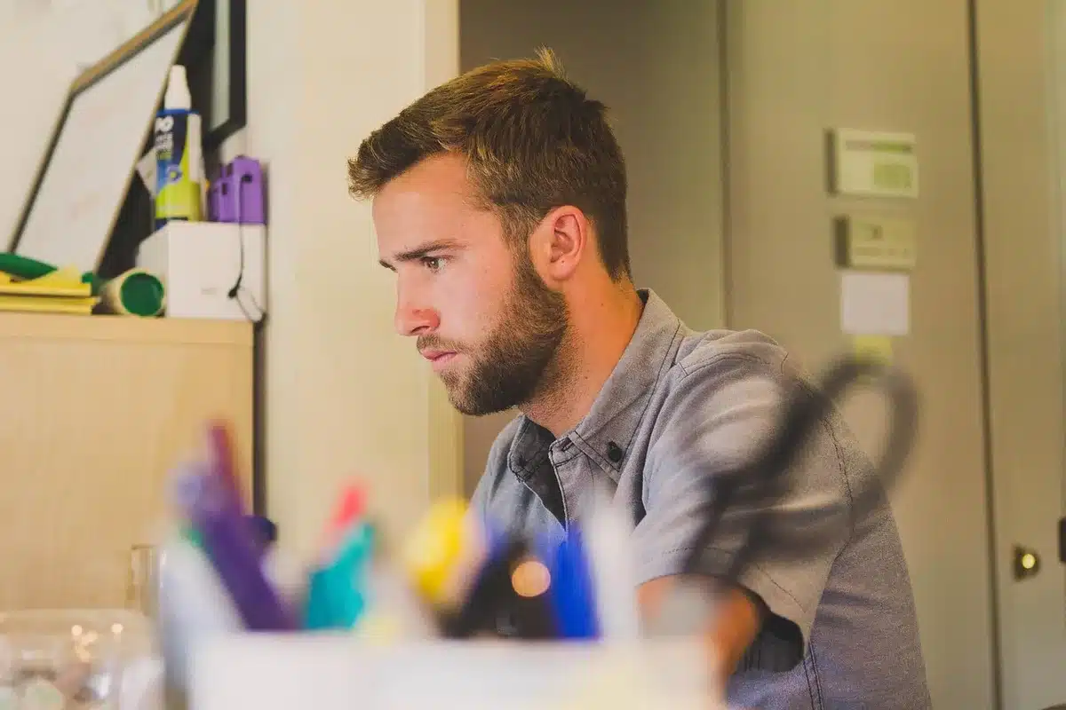 Employé pensif à son bureau, mains sur le visage