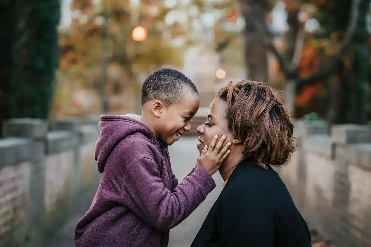 Parent parlant calmement à un enfant assis à une table, geste de soutien
