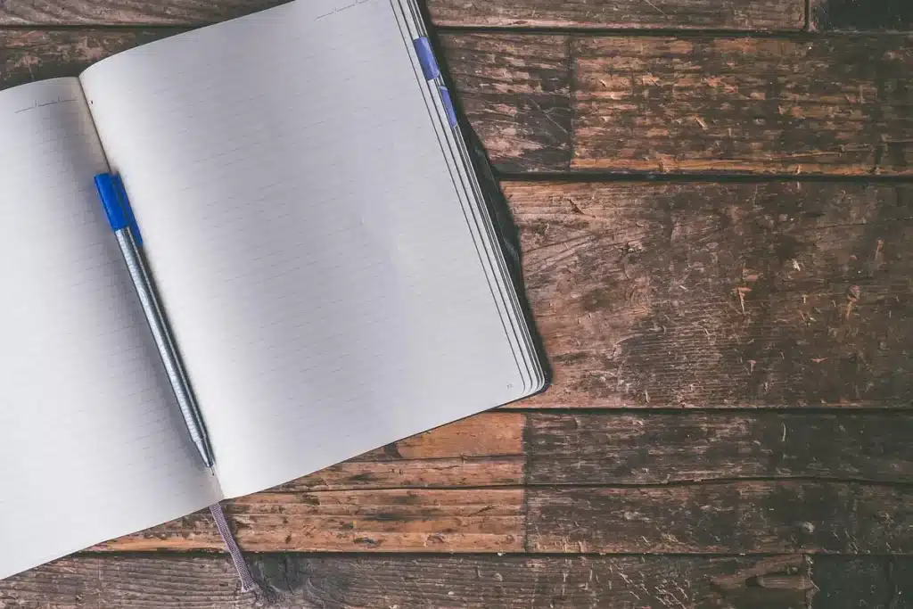 Mains d'adulte prenant des notes sur un carnet près d'une fenêtre en plein jour