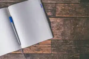 Mains d'adulte prenant des notes sur un carnet près d'une fenêtre en plein jour